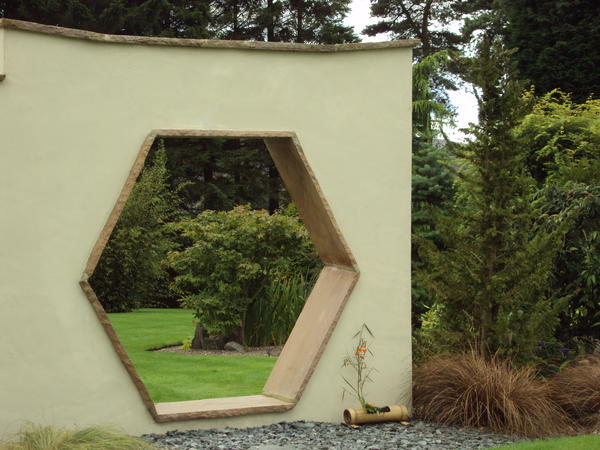 Шестиугольный проем в стене позволяет увидеть фрагменты скрытой части сада