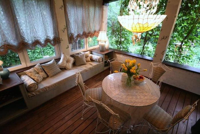 Обеденный столик и мягкий диван на веранде дачного домика